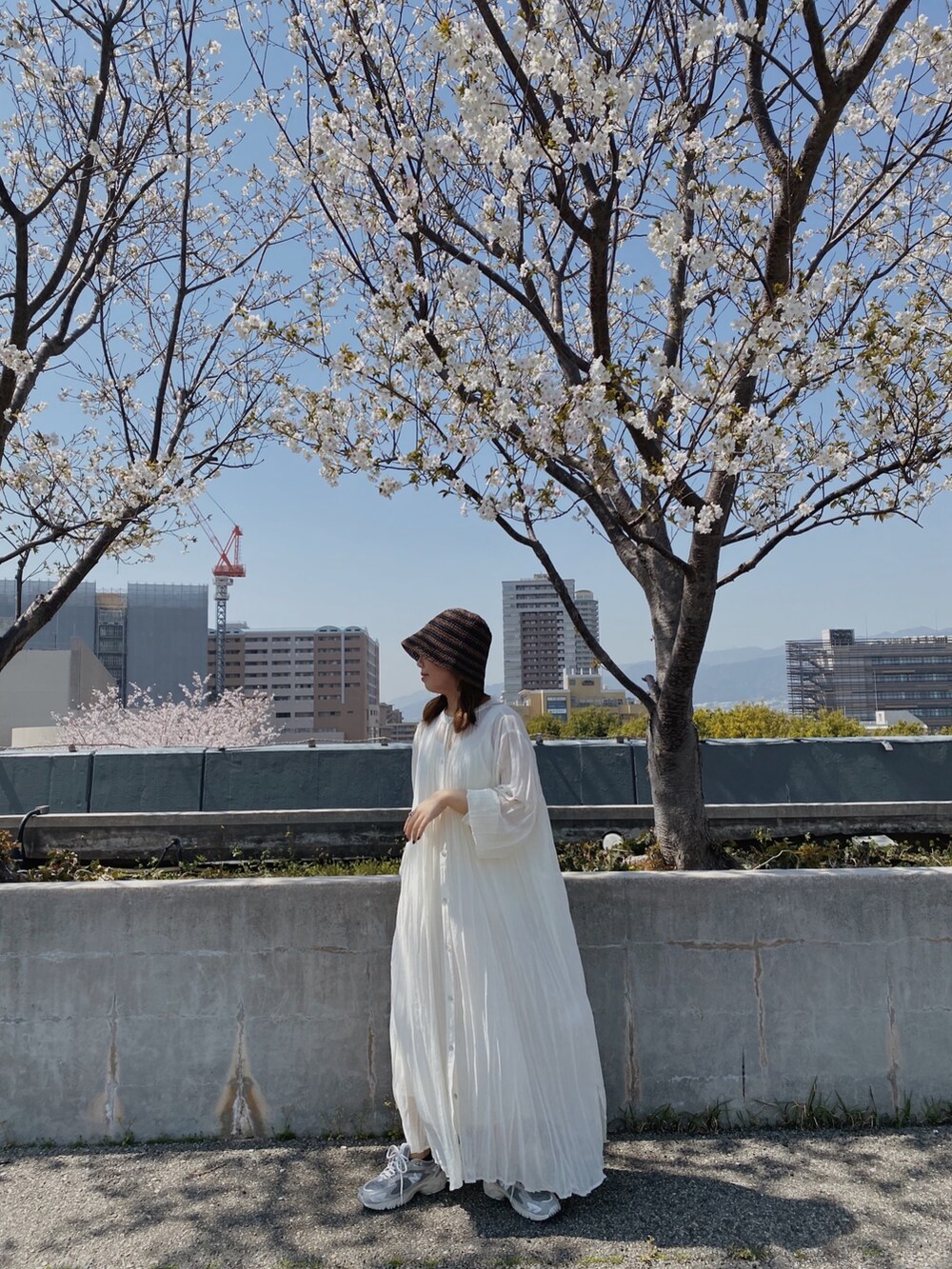 ホワイト系のワンピース、ブラウン系のハットを着用したレディースの春コーディネートの2枚目の写真