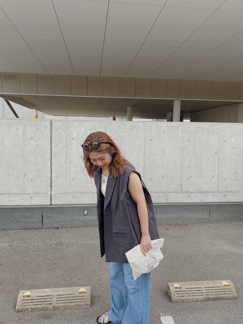 グレー系のテーラードジャケット、ホワイト系のキャミソール、ブルー系のデニムパンツを着用したレディースの春コーディネートの2枚目の写真