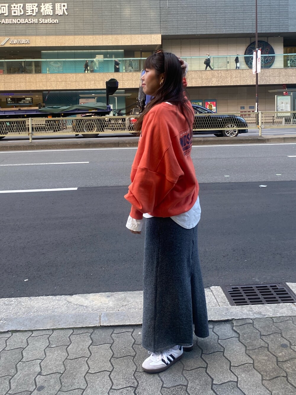 オレンジ系のスウェット、ホワイト系のTシャツ/カットソー、グレー系のスカートを着用したレディースの冬コーディネートの6枚目の写真