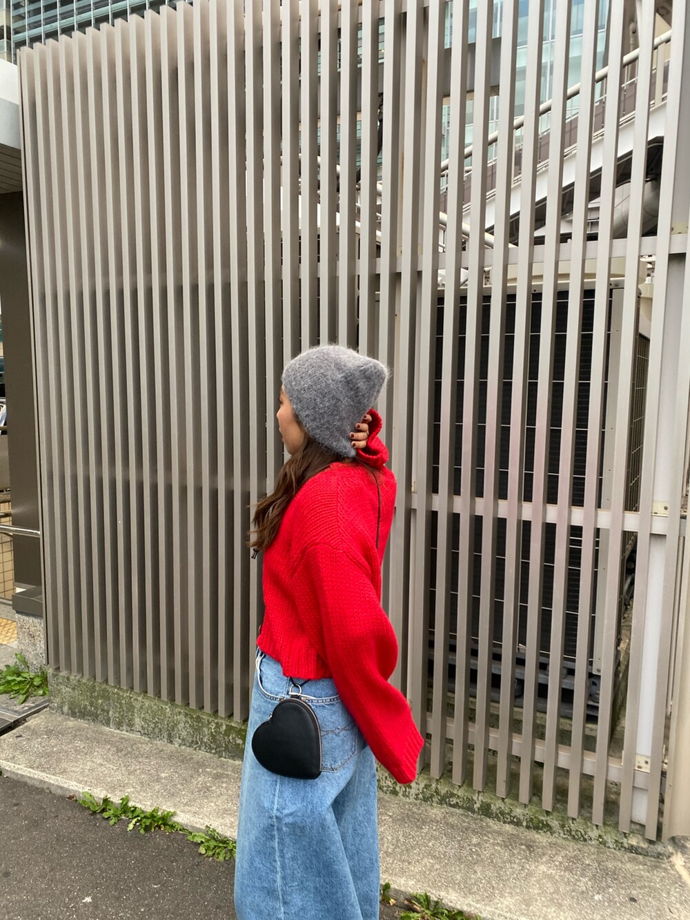 レッド系のカーディガン/ボレロ、ブルー系のデニムパンツ、ブラック系のショルダーバッグを着用したレディースの冬コーディネートの5枚目の写真