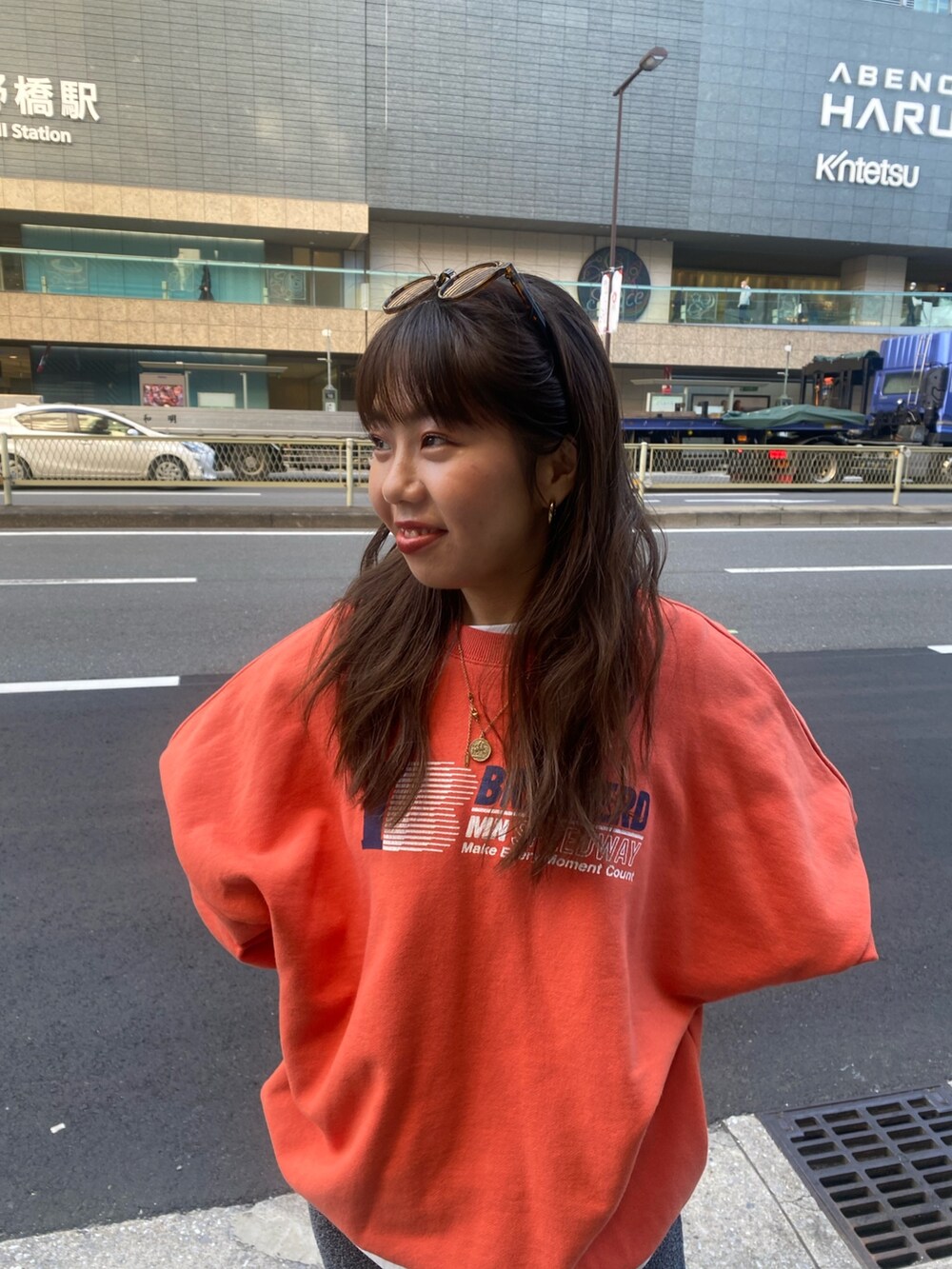 オレンジ系のスウェット、ホワイト系のTシャツ/カットソー、グレー系のスカートを着用したレディースの冬コーディネートの4枚目の写真