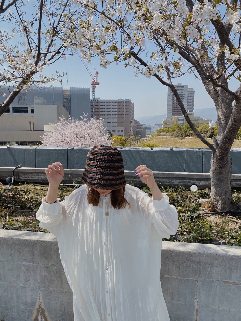 ホワイト系のワンピース、ブラウン系のハットを着用したレディースの春コーディネートの4枚目の写真