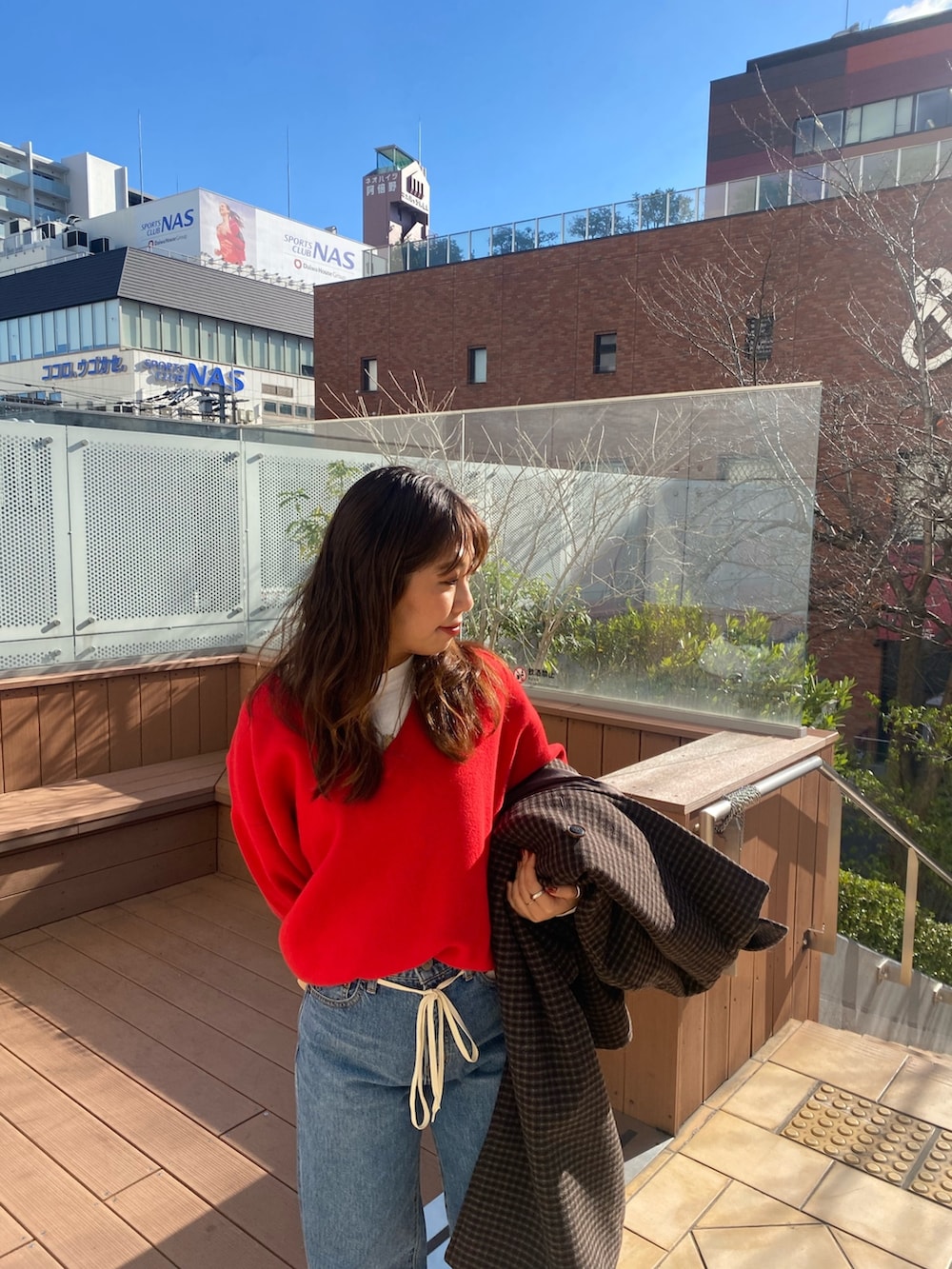 その他のチェスターコート、ブルー系のデニムパンツ、レッド系のニット/セーターを着用したレディースの冬コーディネートの4枚目の写真