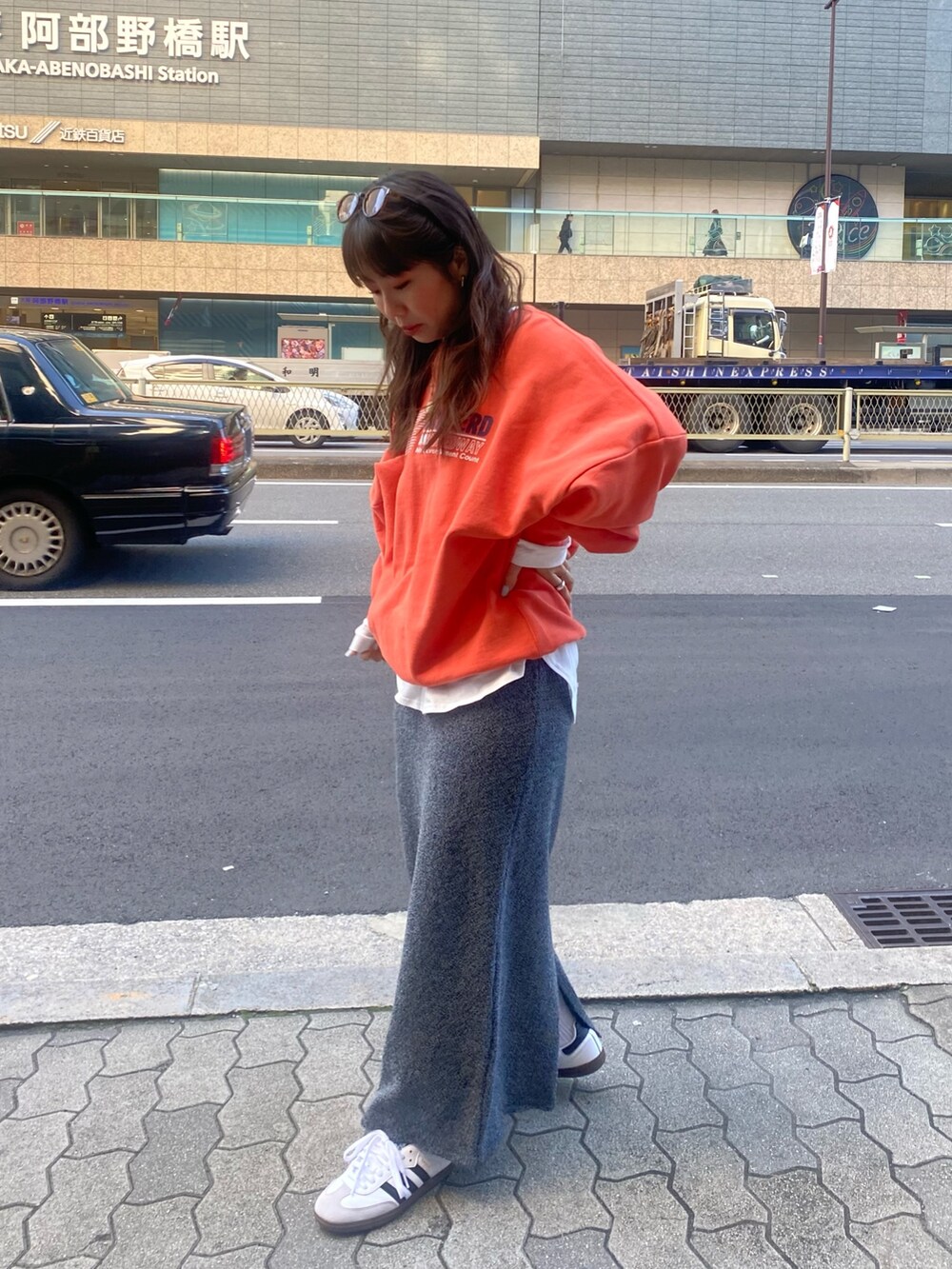 オレンジ系のスウェット、ホワイト系のTシャツ/カットソー、グレー系のスカートを着用したレディースの冬コーディネートの2枚目の写真