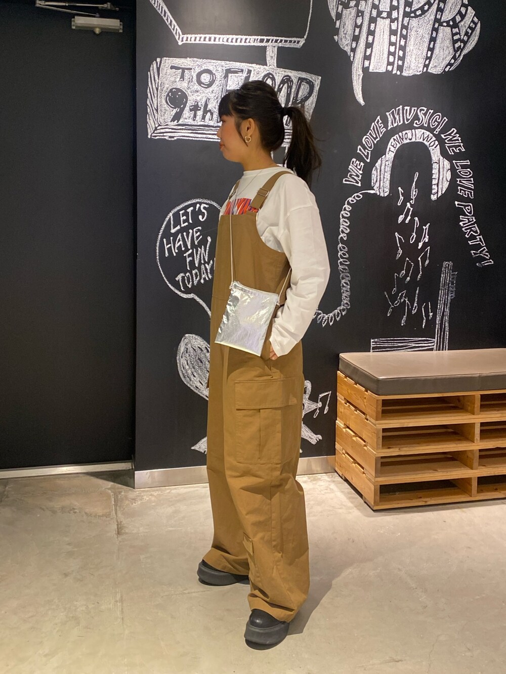 イエロー系のつなぎ/オールインワン、ホワイト系のTシャツ/カットソー、シルバー系のショルダーバッグを着用したレディースの冬コーディネートの2枚目の写真