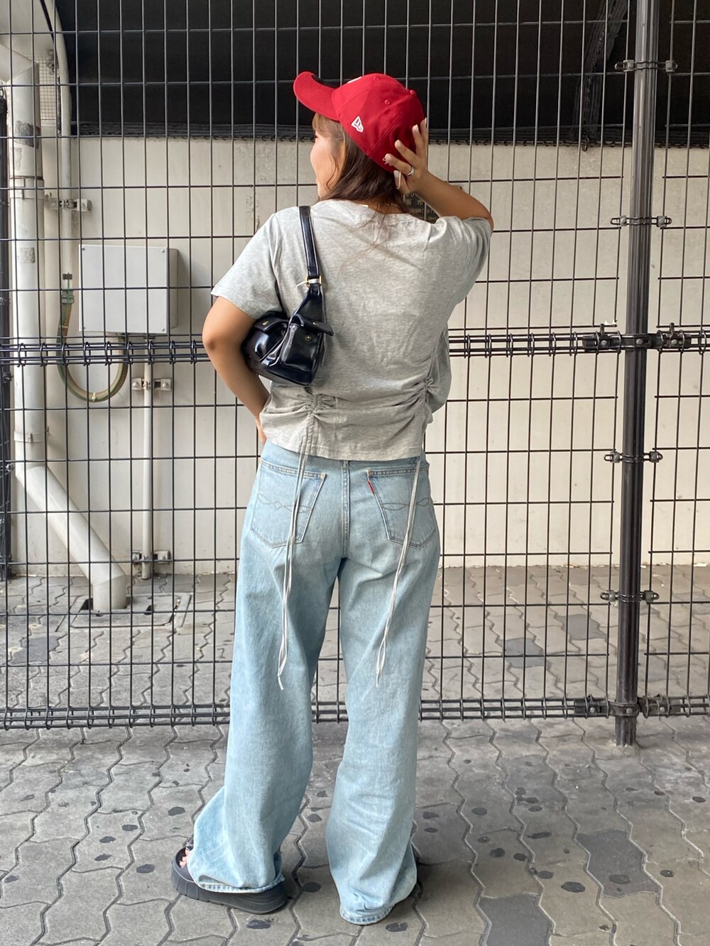 グレー系のTシャツ/カットソー、ブルー系のデニムパンツ、ブラック系のハンドバッグを着用したレディースの夏コーディネートの3枚目の写真