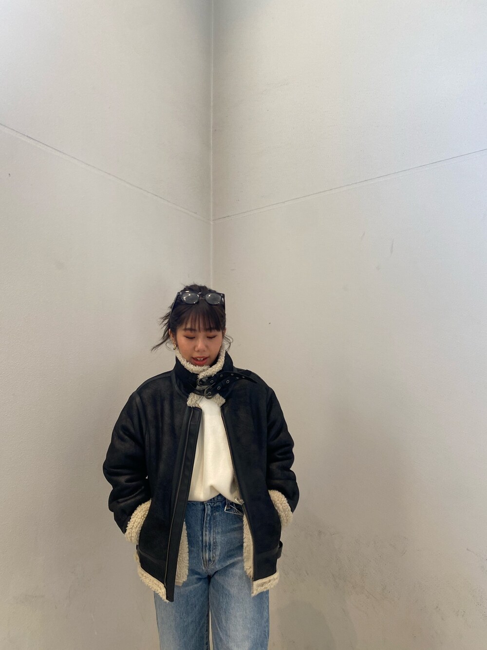 ブラック系のムートンコート、ブルー系のデニムパンツを着用したレディースの冬コーディネートの5枚目の写真