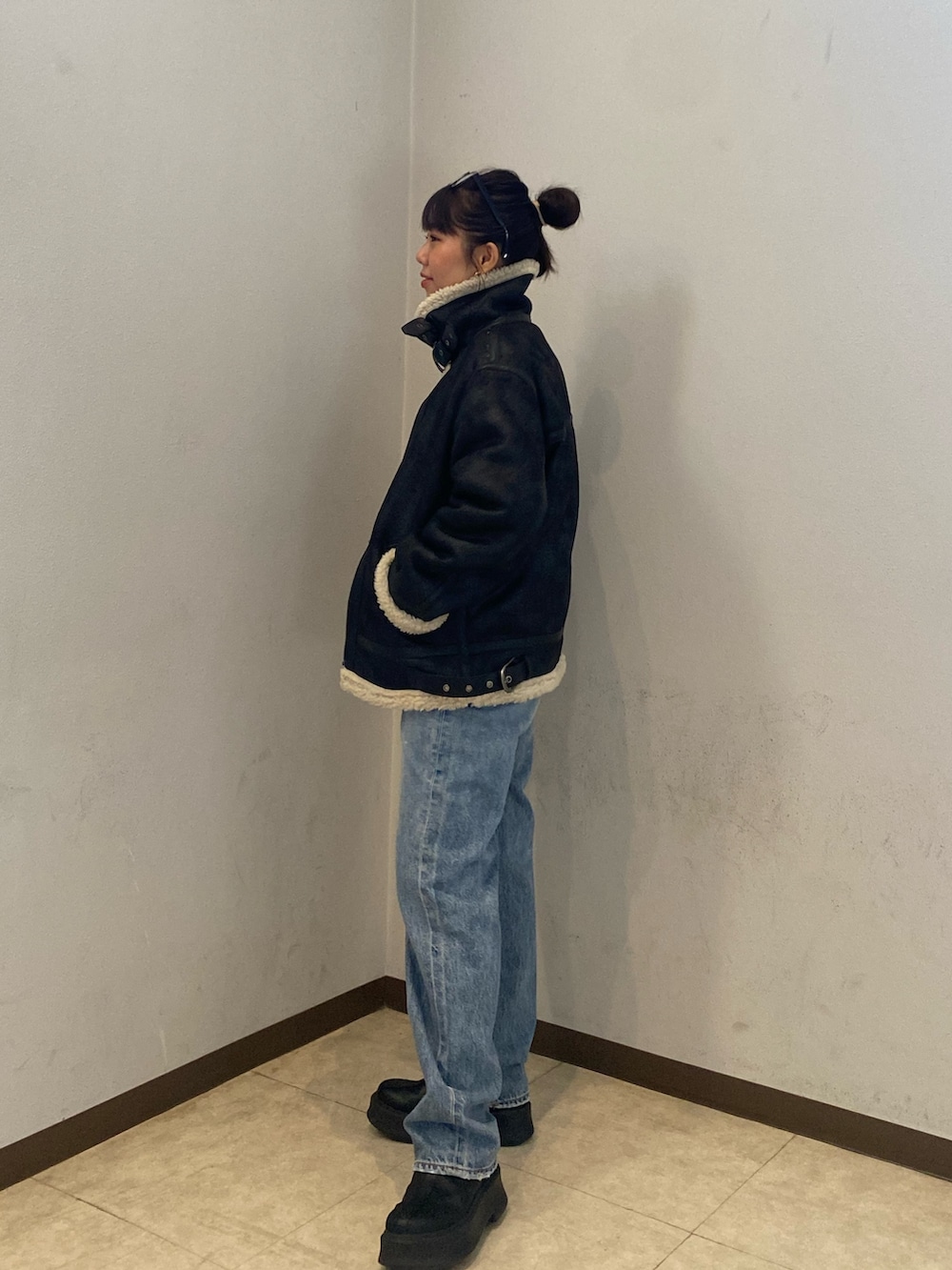 ブラック系のムートンコート、ブルー系のデニムパンツを着用したレディースの冬コーディネートの3枚目の写真