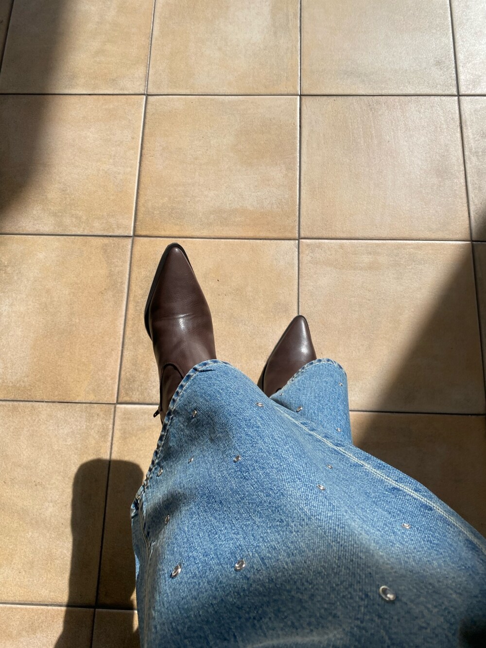 ブラック系のニット/セーター、ブルー系のデニムパンツ、ブラウン系のブーツを着用したレディースの秋コーディネートの4枚目の写真