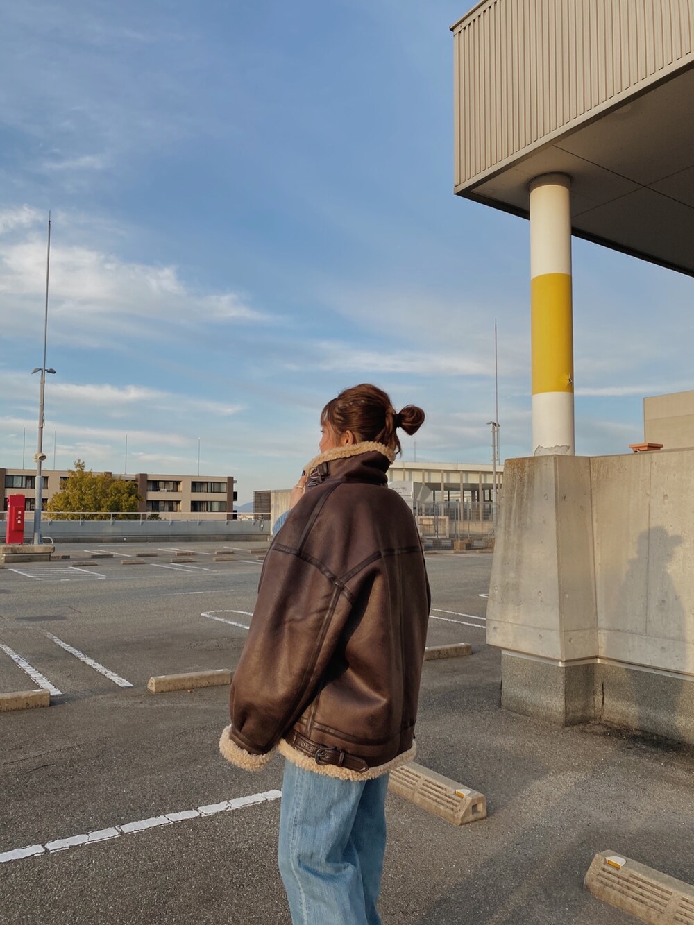 ブラウン系のムートンコート、ブルー系のデニムパンツ、ブルー系のニット/セーターを着用したレディースの冬コーディネートの3枚目の写真