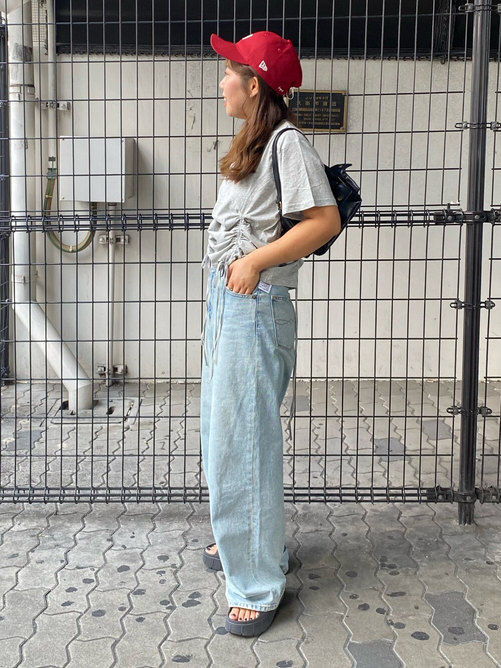 グレー系のTシャツ/カットソー、ブルー系のデニムパンツ、ブラック系のハンドバッグを着用したレディースの夏コーディネートの2枚目の写真