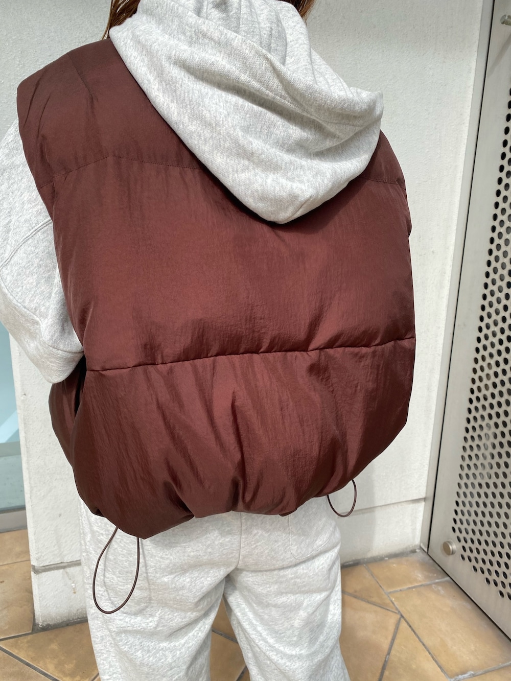 ブラウン系のダウンベスト、グレー系のスウェットパンツ、グレー系のパーカーを着用したレディースの秋コーディネートの5枚目の写真