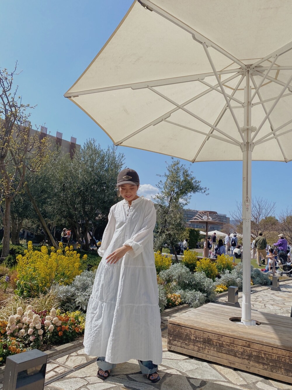 ホワイト系のワンピース、ブルー系のデニムパンツ、その他のサンダルを着用したレディースの春コーディネートの3枚目の写真