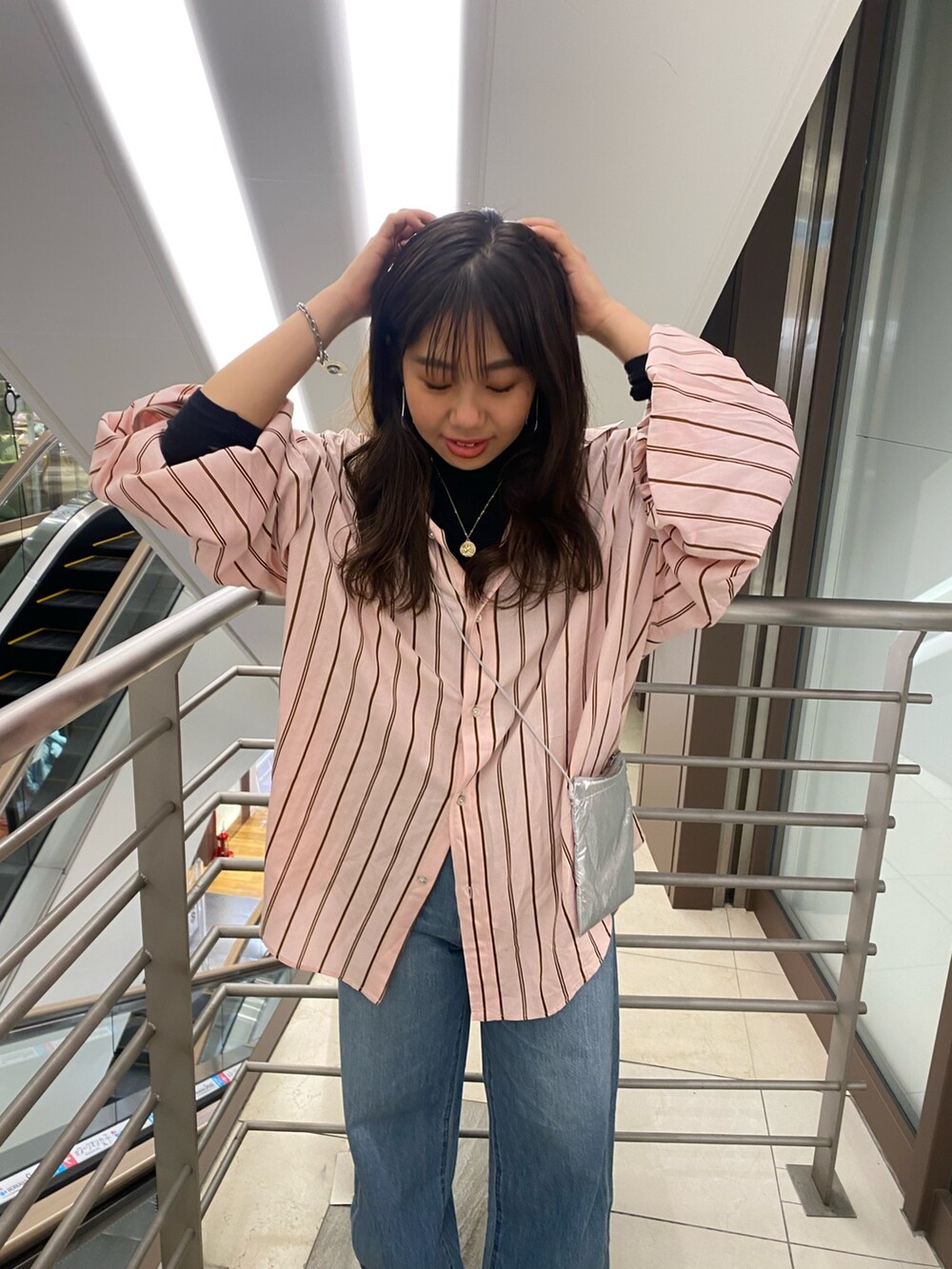 ピンク系のシャツ/ブラウス、ブルー系のデニムパンツ、シルバー系のショルダーバッグを着用したレディースの冬コーディネートの4枚目の写真