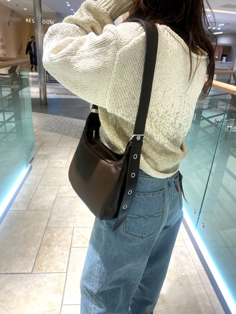 ホワイト系のニット/セーター、ブルー系のデニムパンツ、ブラウン系のショルダーバッグを着用したレディースの冬コーディネートの6枚目の写真