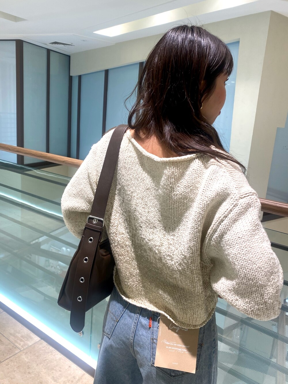 ホワイト系のニット/セーター、ブルー系のデニムパンツ、ブラウン系のショルダーバッグを着用したレディースの冬コーディネートの7枚目の写真