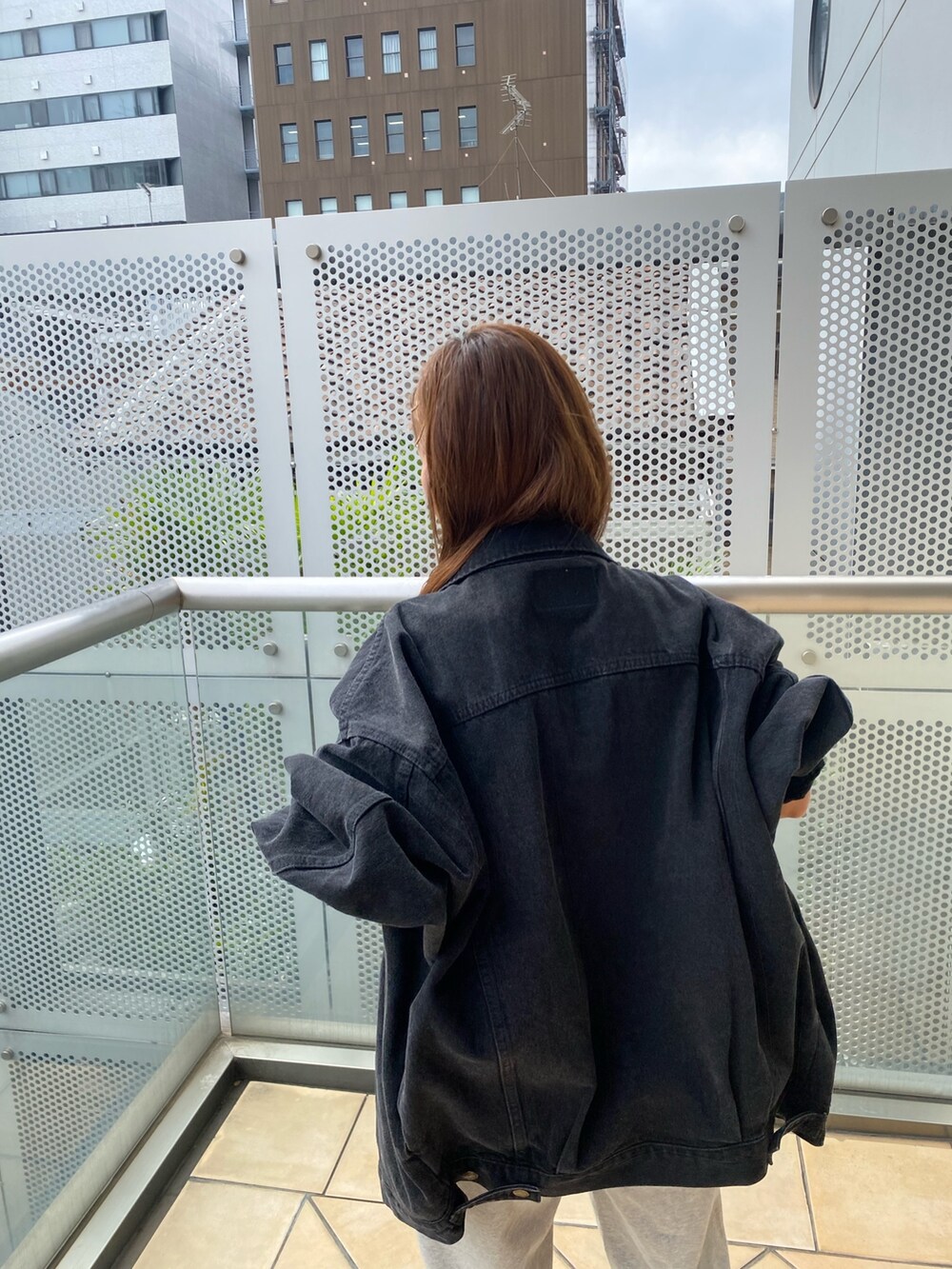 ブラック系のデニムジャケット、グレー系のスウェットパンツを着用したレディースの秋コーディネートの4枚目の写真