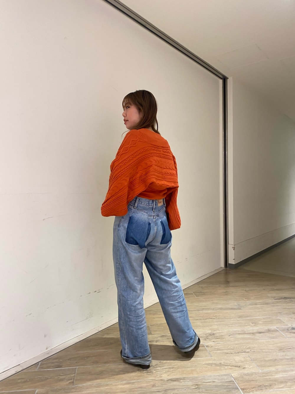 オレンジ系のカーディガン/ボレロ、ブルー系のデニムパンツ、ブラック系のブーツを着用したレディースの秋コーディネートの3枚目の写真