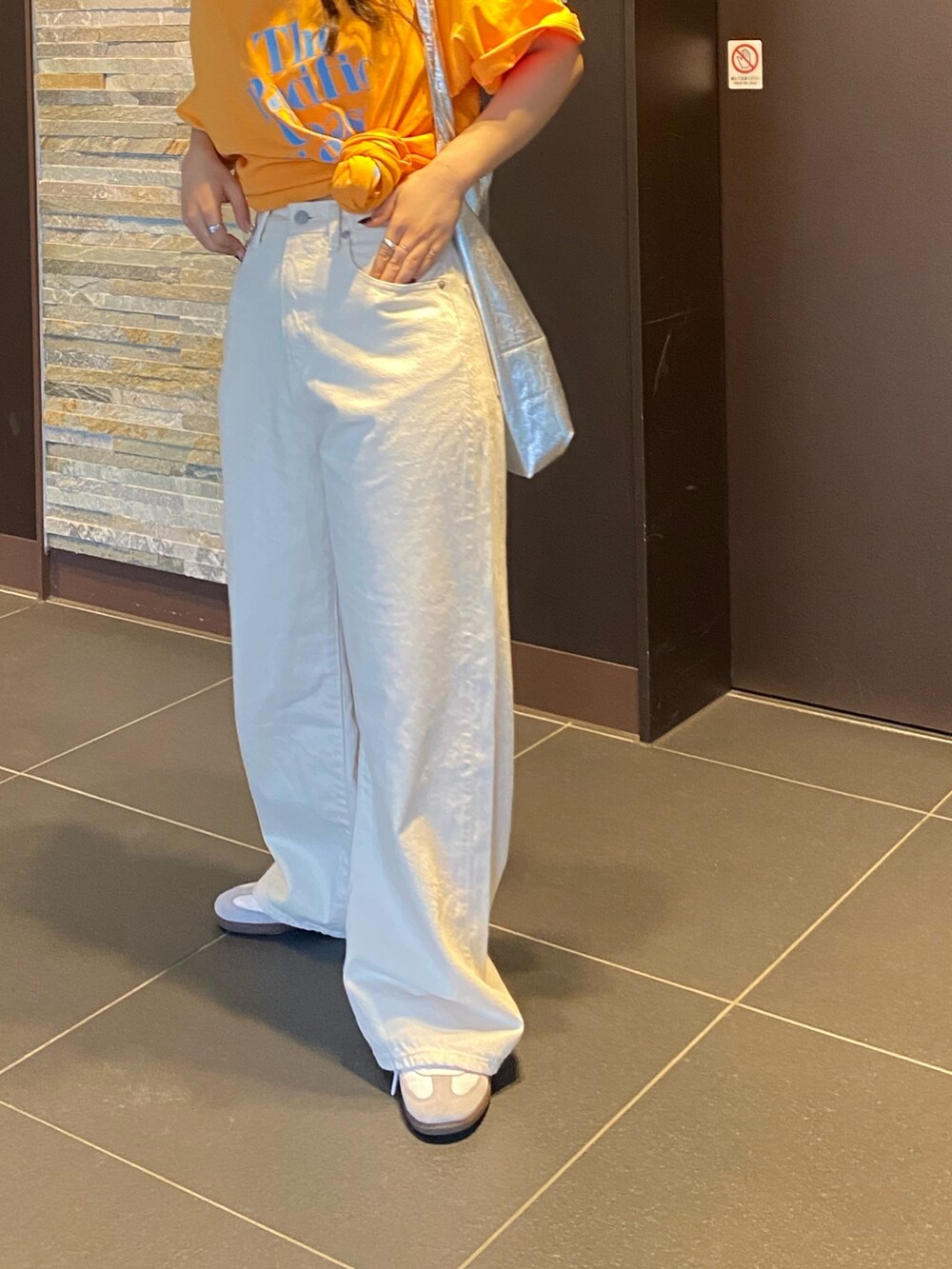 オレンジ系のTシャツ/カットソー、ホワイト系のデニムパンツを着用したレディースの春コーディネートの7枚目の写真