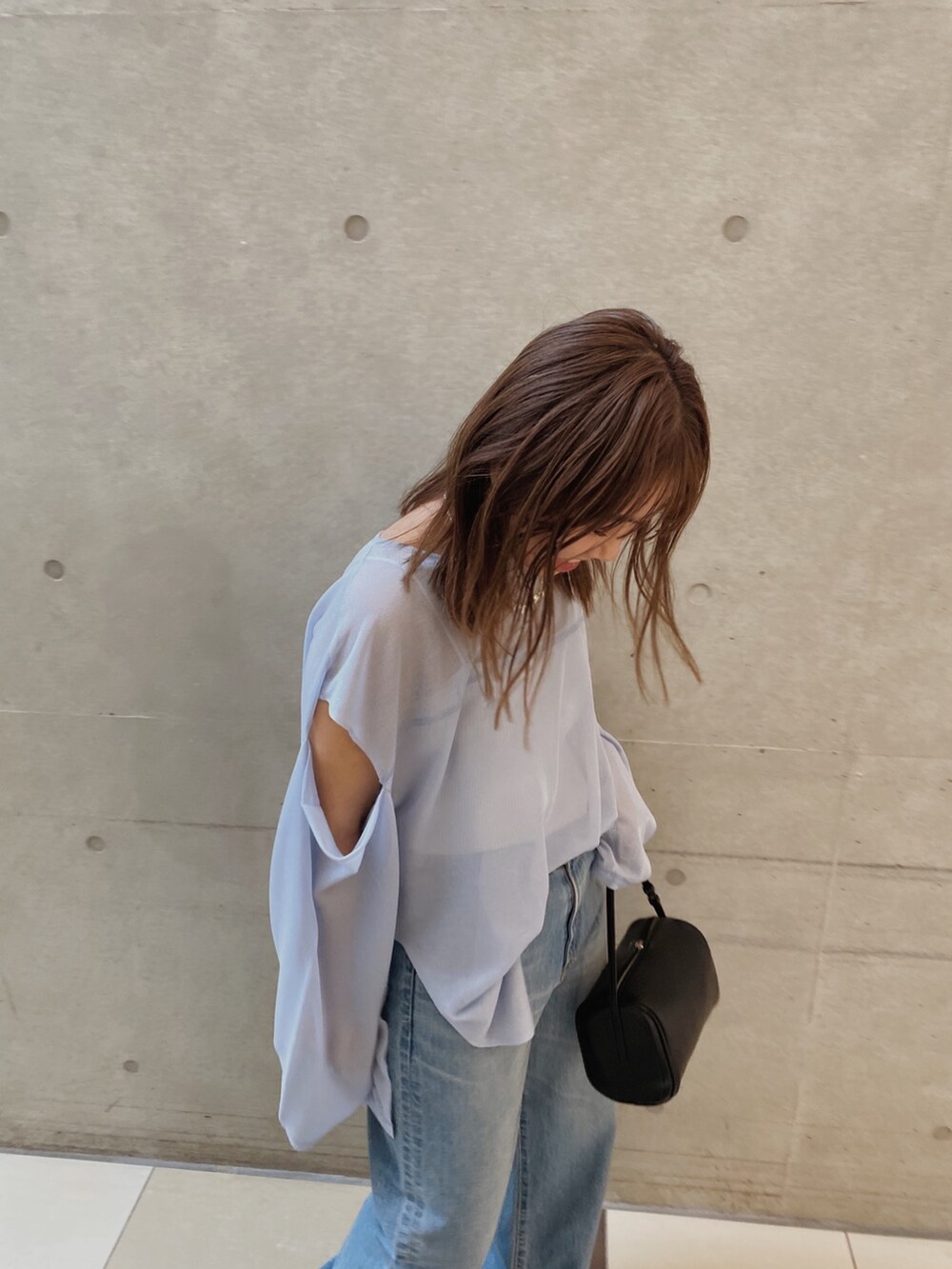 ブルー系のニット/セーター、ブルー系のデニムパンツ、ブラック系のハンドバッグを着用したレディースの春コーディネートの2枚目の写真