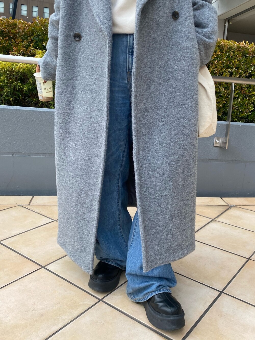 グレー系のチェスターコート、ホワイト系のパーカー、ブルー系のデニムパンツを着用したレディースの冬コーディネートの6枚目の写真