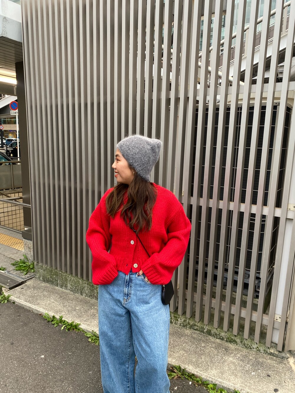 レッド系のカーディガン/ボレロ、ブルー系のデニムパンツ、ブラック系のショルダーバッグを着用したレディースの冬コーディネートの4枚目の写真