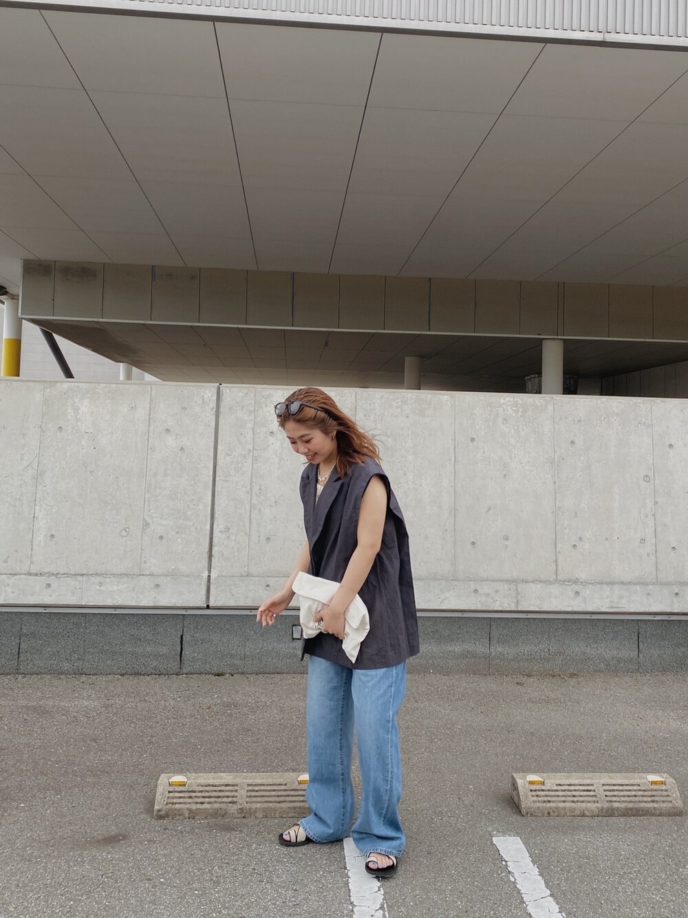 グレー系のテーラードジャケット、ホワイト系のキャミソール、ブルー系のデニムパンツを着用したレディースの春コーディネートの3枚目の写真