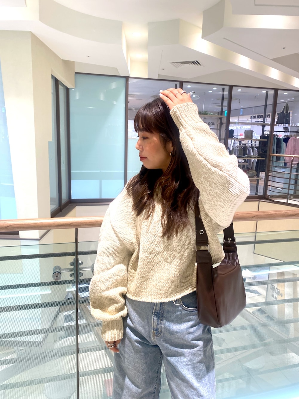 ホワイト系のニット/セーター、ブルー系のデニムパンツ、ブラウン系のショルダーバッグを着用したレディースの冬コーディネートの4枚目の写真