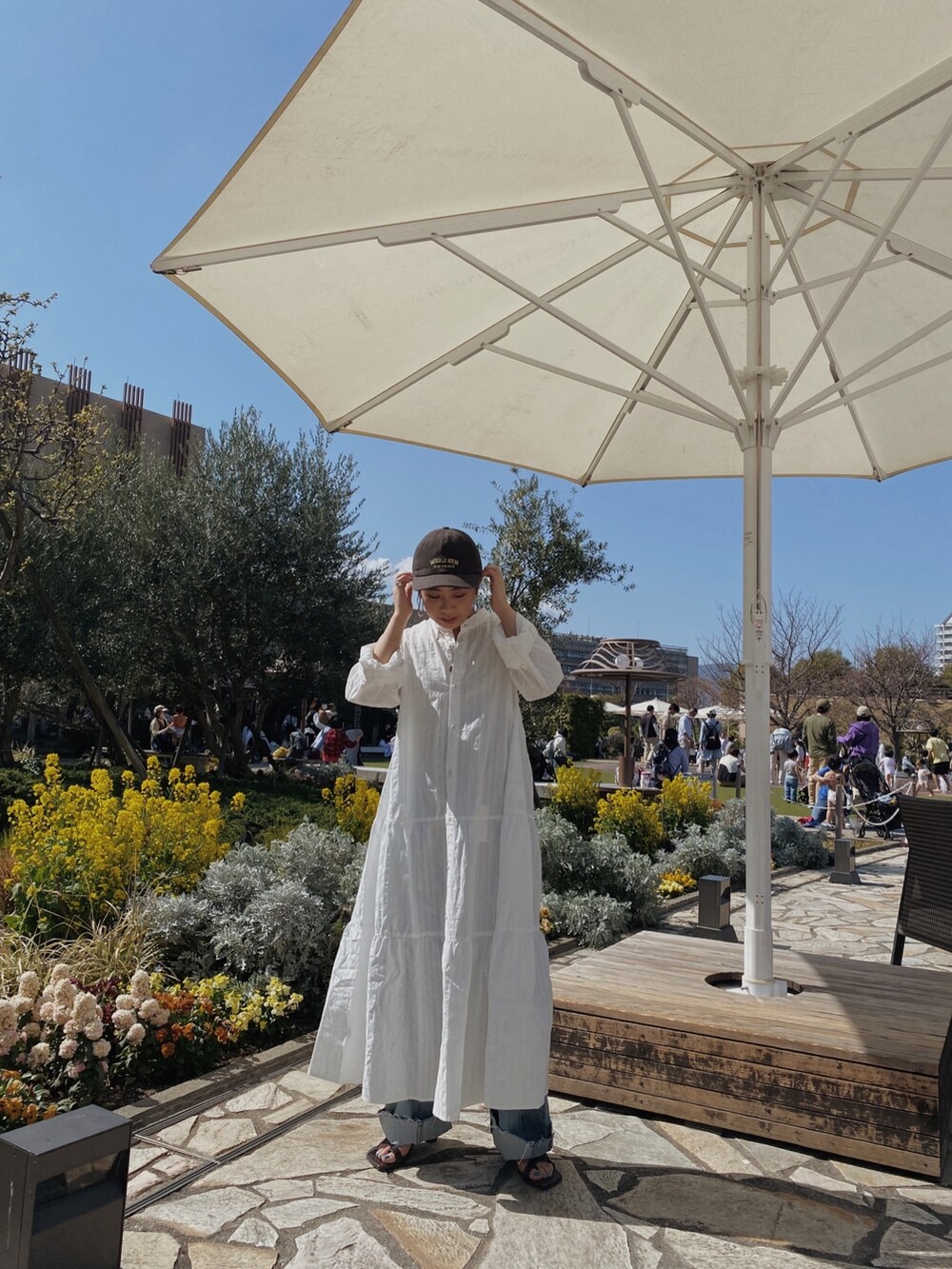 ホワイト系のワンピース、ブルー系のデニムパンツ、その他のサンダルを着用したレディースの春コーディネートの2枚目の写真