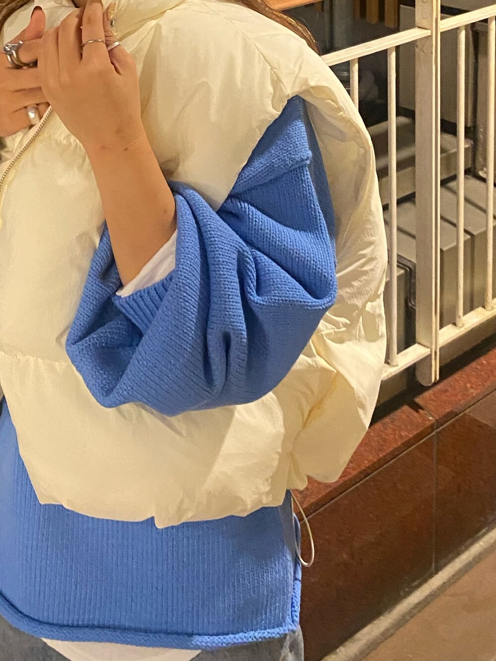 ホワイト系のダウンベスト、ブルー系のニット/セーター、ブルー系のデニムパンツを着用したレディースの秋コーディネートの8枚目の写真