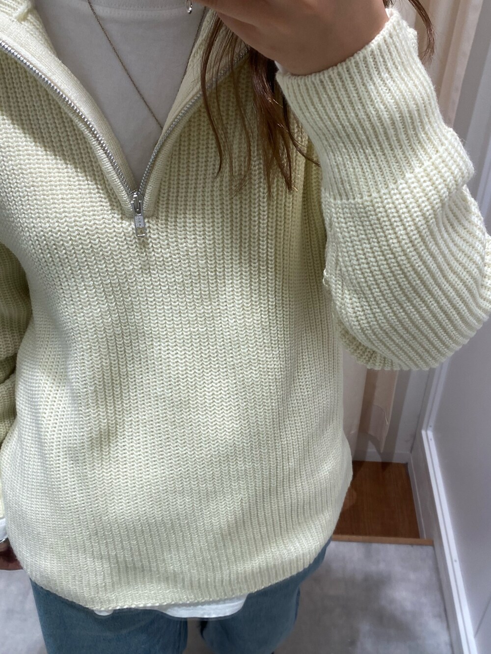 ホワイト系のニット/セーター、ブルー系のデニムパンツ、ホワイト系のTシャツ/カットソーを着用したレディースの冬コーディネートの5枚目の写真