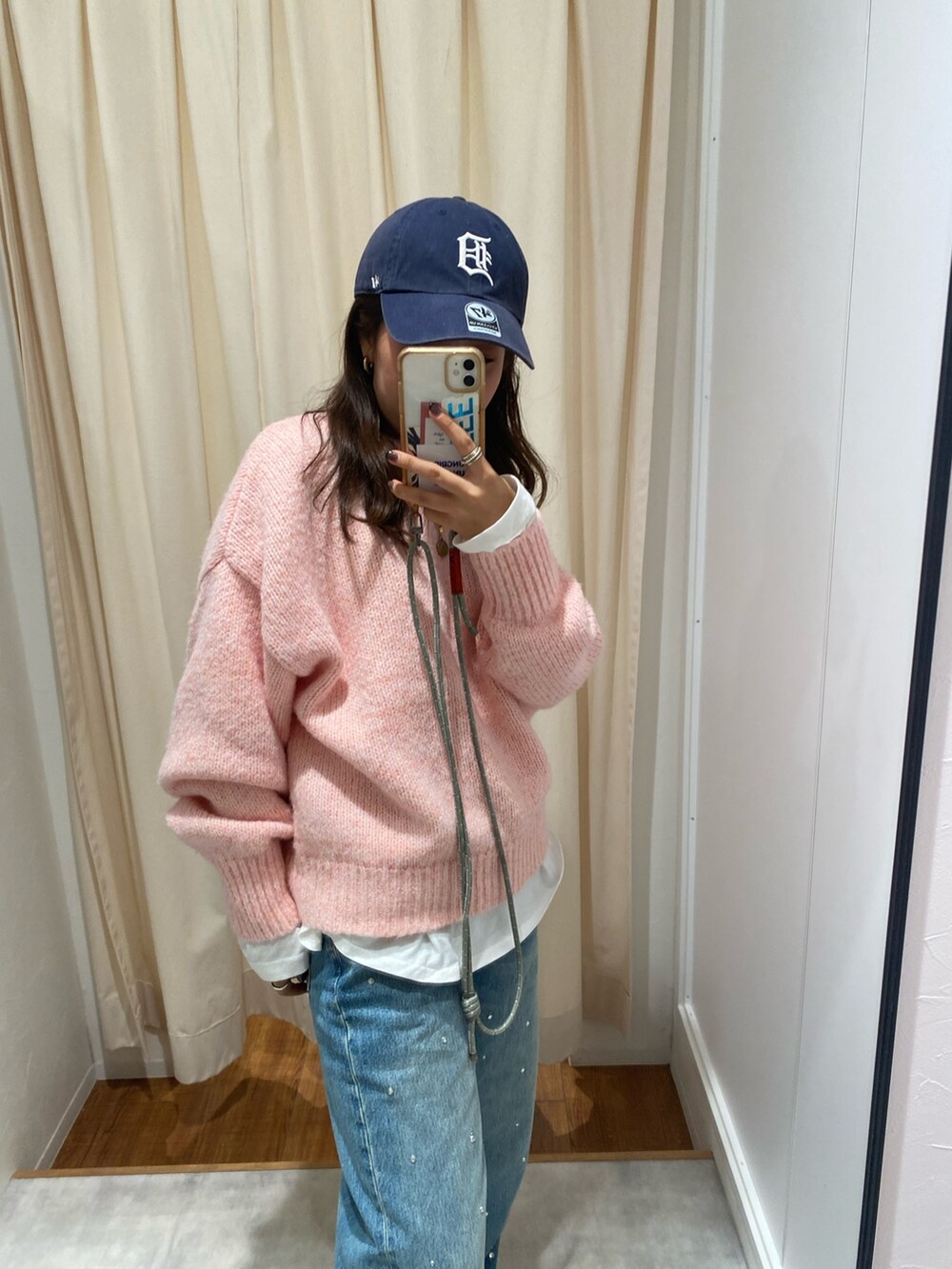 ピンク系のニット/セーター、ホワイト系のTシャツ/カットソー、ブルー系のデニムパンツを着用したレディースの秋コーディネートの5枚目の写真