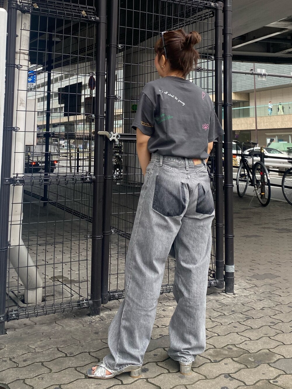 グレー系のTシャツ/カットソー、ブラック系のデニムパンツ、シルバー系のサンダルを着用したレディースの春コーディネートの4枚目の写真