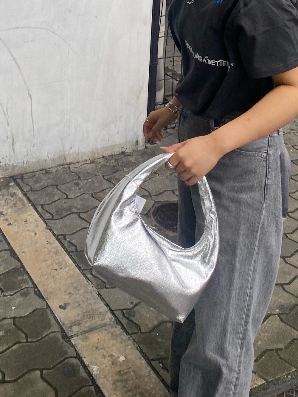 グレー系のTシャツ/カットソー、ブラック系のデニムパンツ、シルバー系のサンダルを着用したレディースの春コーディネートの6枚目の写真