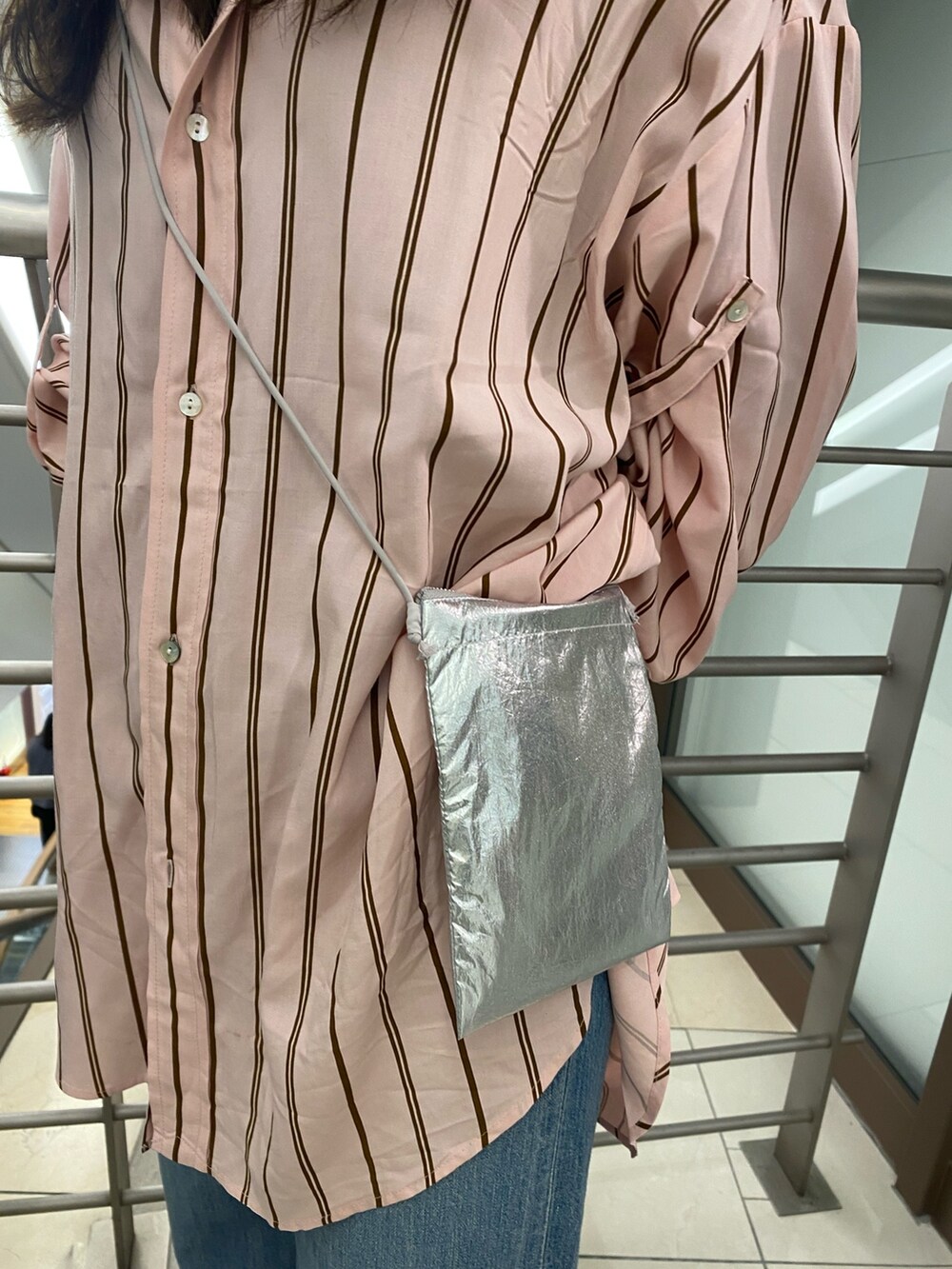 ピンク系のシャツ/ブラウス、ブルー系のデニムパンツ、シルバー系のショルダーバッグを着用したレディースの冬コーディネートの5枚目の写真