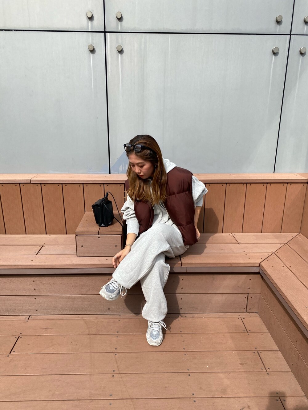 ブラウン系のダウンベスト、グレー系のスウェットパンツ、グレー系のパーカーを着用したレディースの秋コーディネートの2枚目の写真