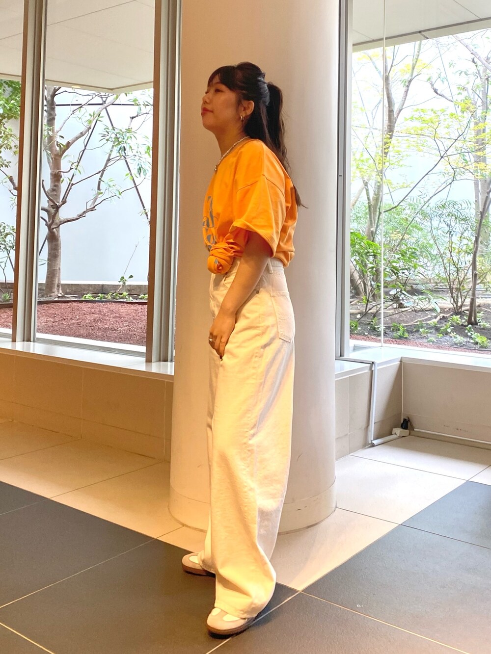 オレンジ系のTシャツ/カットソー、ホワイト系のデニムパンツを着用したレディースの春コーディネートの2枚目の写真