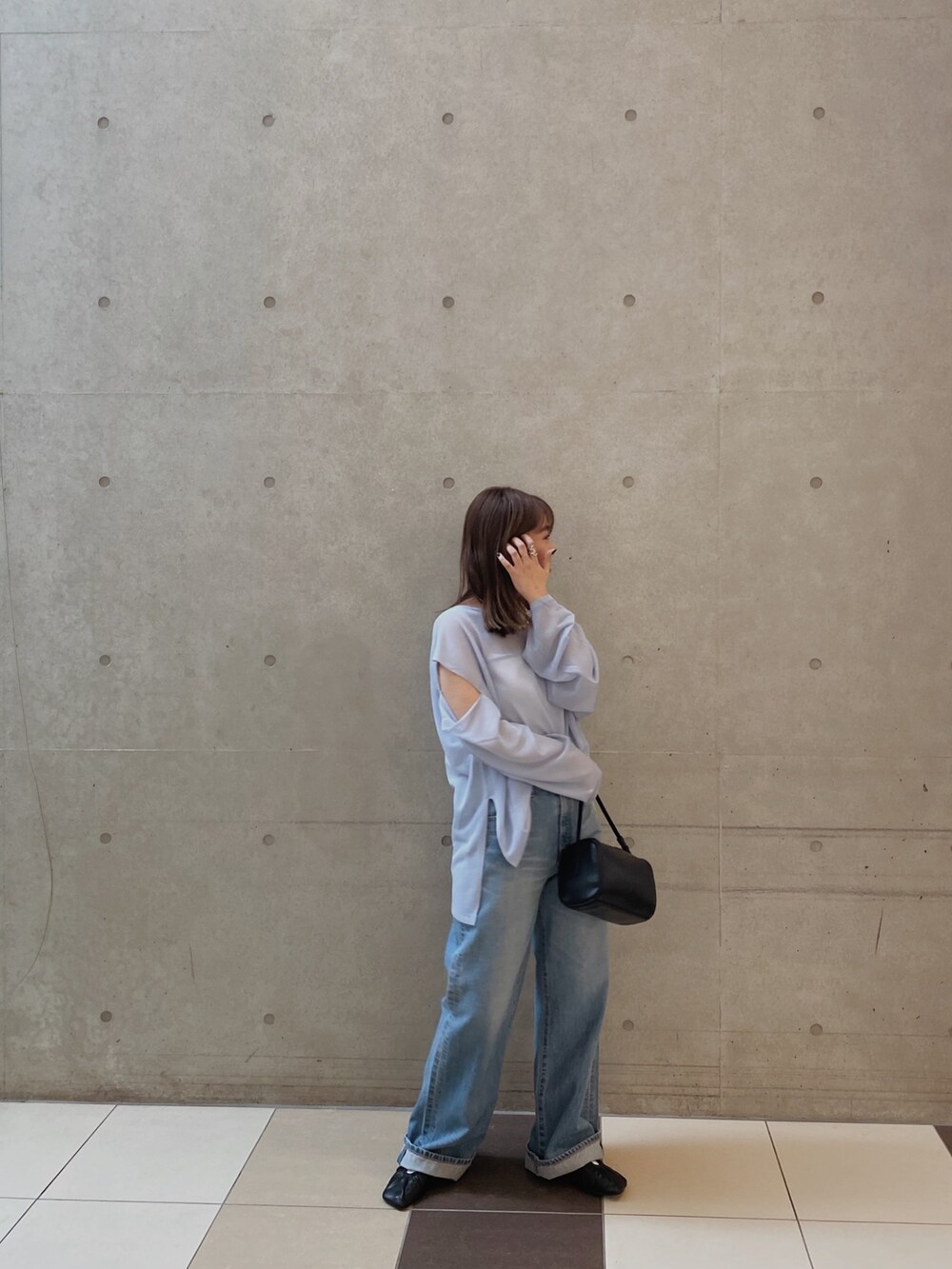 ブルー系のニット/セーター、ブルー系のデニムパンツ、ブラック系のハンドバッグを着用したレディースの春コーディネートの3枚目の写真