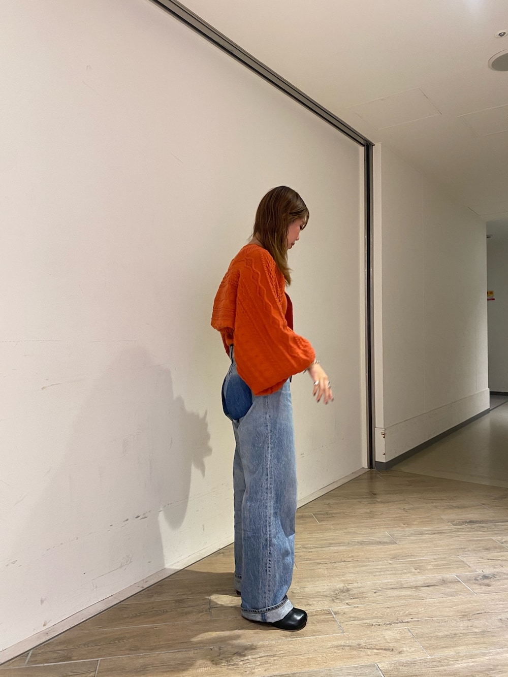 オレンジ系のカーディガン/ボレロ、ブルー系のデニムパンツ、ブラック系のブーツを着用したレディースの秋コーディネートの2枚目の写真