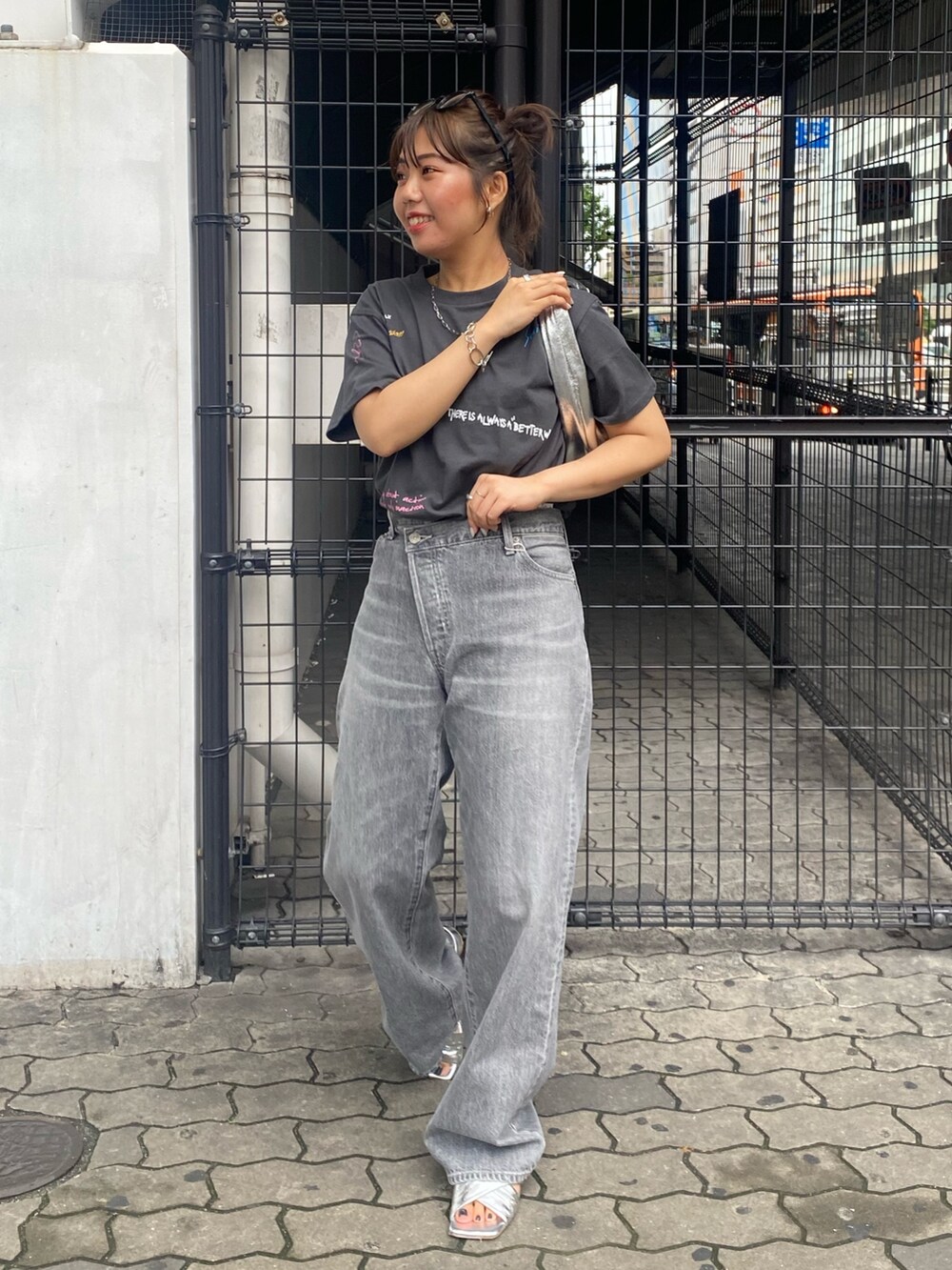 グレー系のTシャツ/カットソー、ブラック系のデニムパンツ、シルバー系のサンダルを着用したレディースの春コーディネートの2枚目の写真