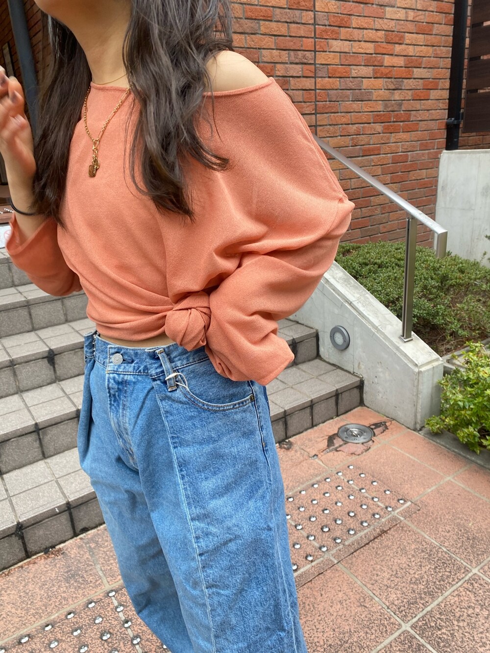 オレンジ系のニット/セーター、ブルー系のデニムパンツ、ブラック系のサンダルを着用したレディースの春コーディネートの4枚目の写真