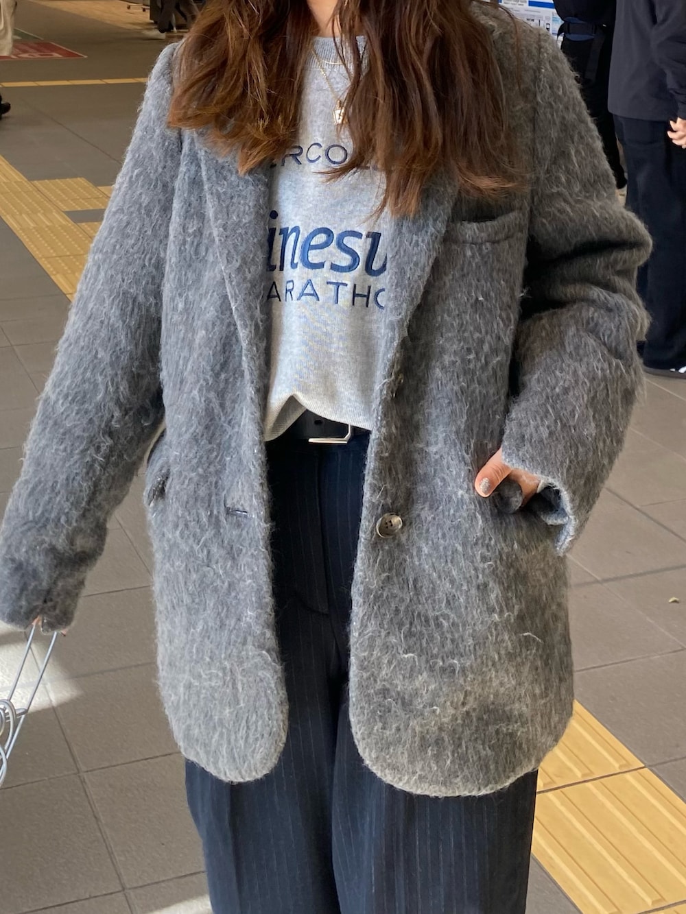 グレー系のテーラードジャケット、グレー系のニット/セーター、シルバー系のショルダーバッグを着用したレディースの冬コーディネートの6枚目の写真