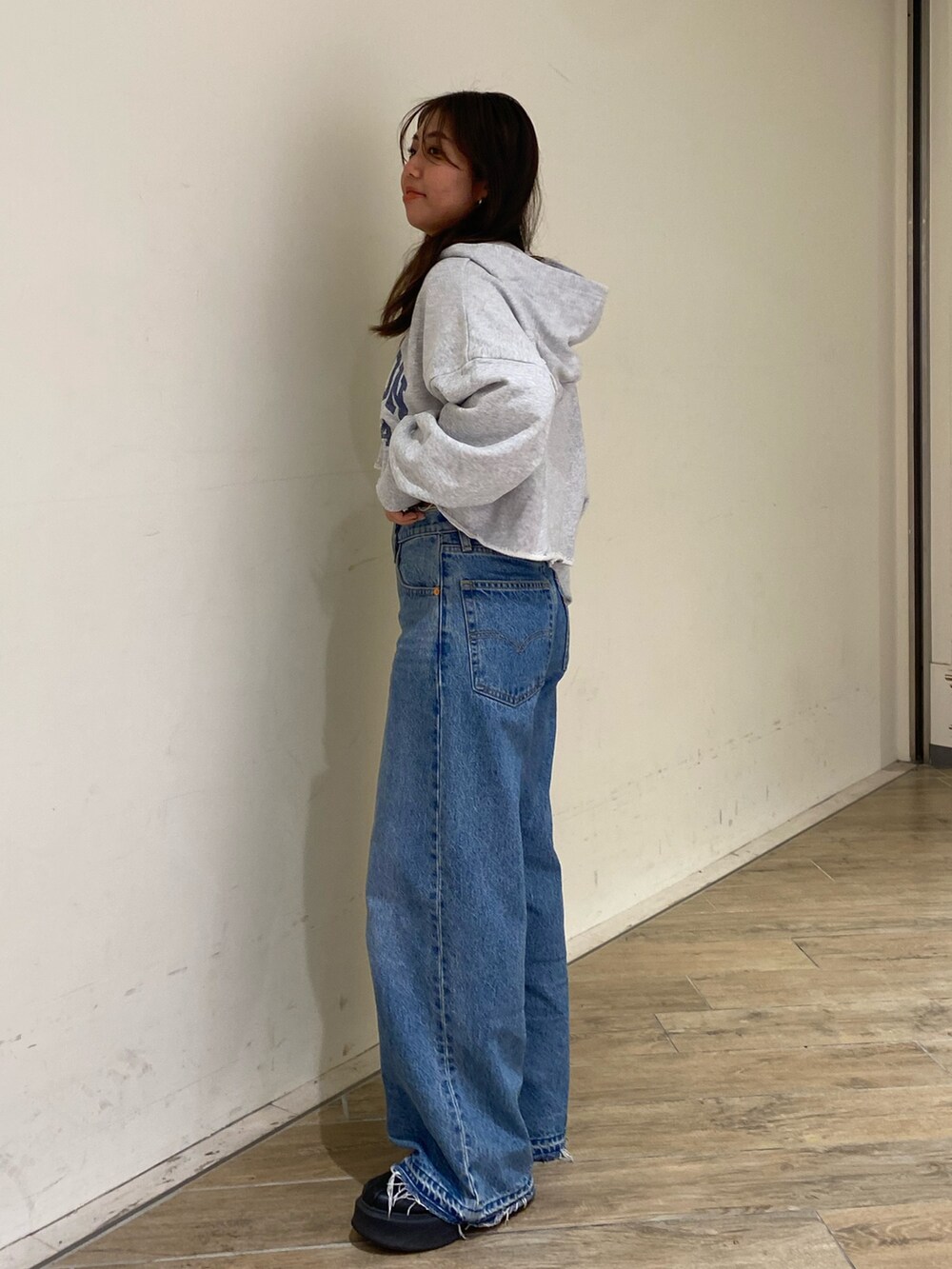 グレー系のパーカー、ブルー系のデニムパンツを着用したレディースの秋コーディネートの2枚目の写真