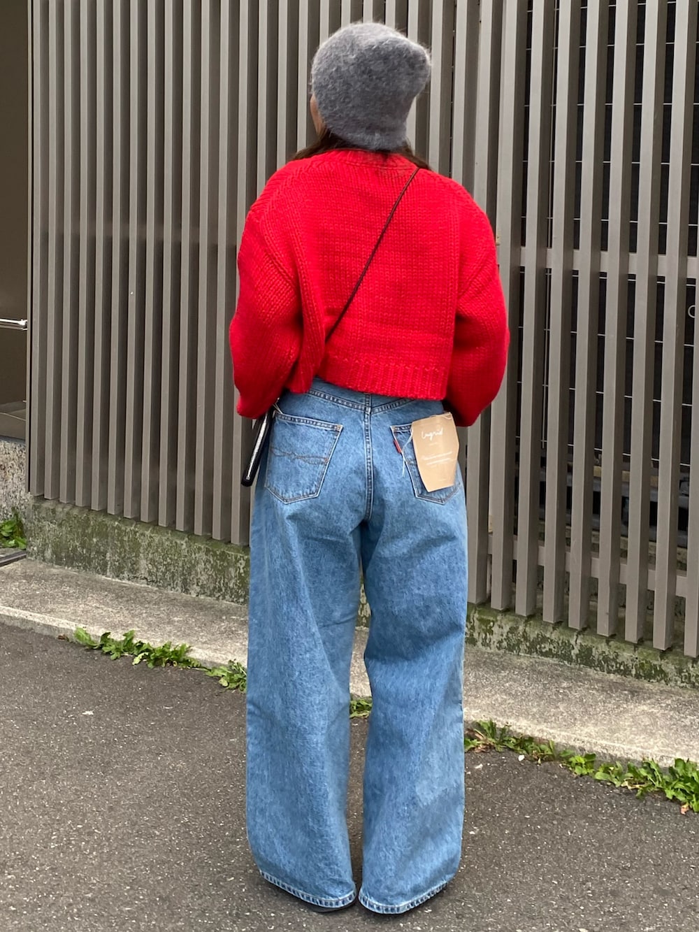 レッド系のカーディガン/ボレロ、ブルー系のデニムパンツ、ブラック系のショルダーバッグを着用したレディースの冬コーディネートの3枚目の写真