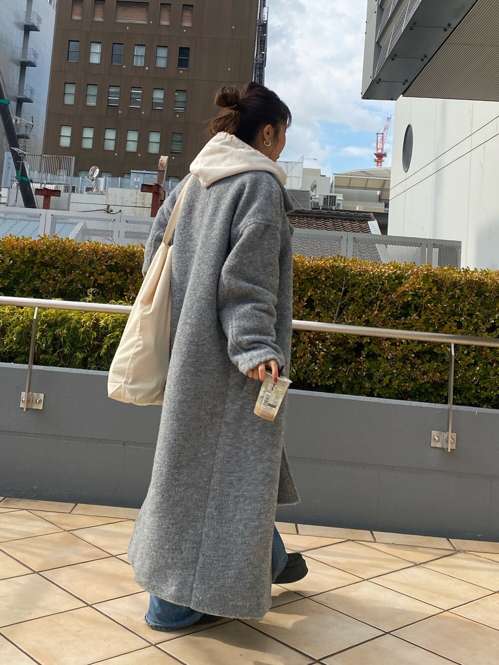 グレー系のチェスターコート、ホワイト系のパーカー、ブルー系のデニムパンツを着用したレディースの冬コーディネートの3枚目の写真