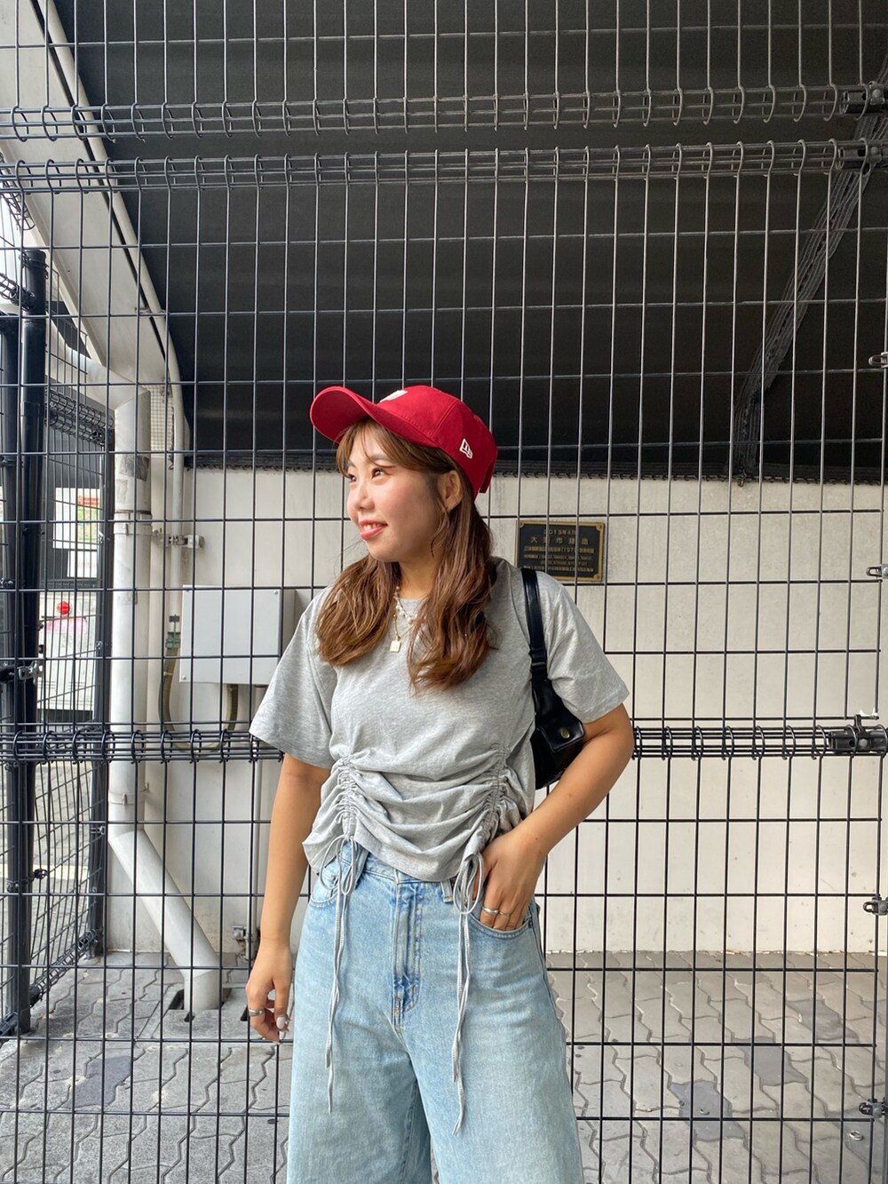 グレー系のTシャツ/カットソー、ブルー系のデニムパンツ、ブラック系のハンドバッグを着用したレディースの夏コーディネートの4枚目の写真