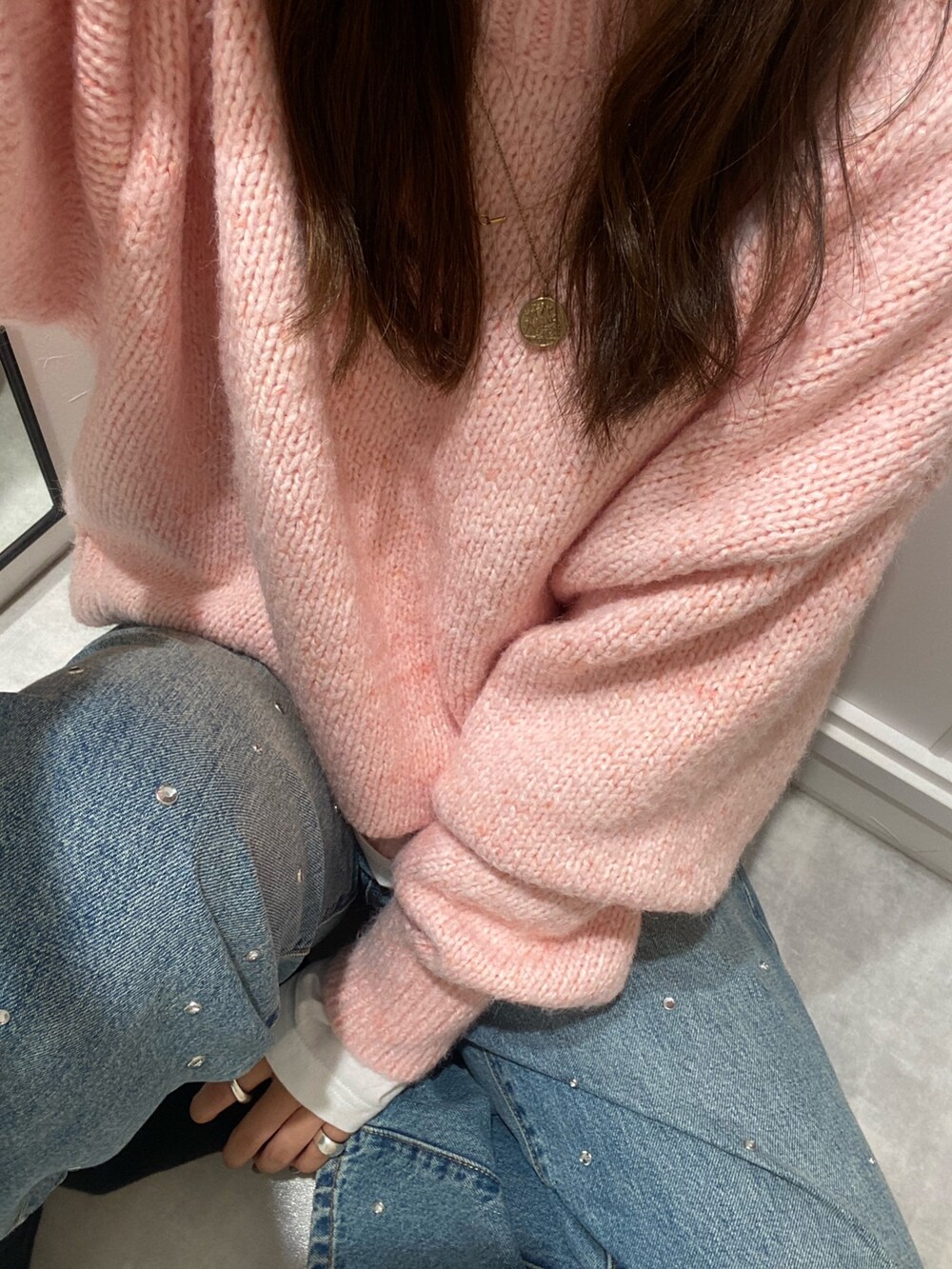 ピンク系のニット/セーター、ホワイト系のTシャツ/カットソー、ブルー系のデニムパンツを着用したレディースの秋コーディネートの4枚目の写真