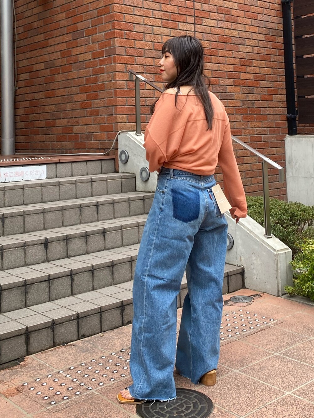 オレンジ系のニット/セーター、ブルー系のデニムパンツ、ブラック系のサンダルを着用したレディースの春コーディネートの3枚目の写真