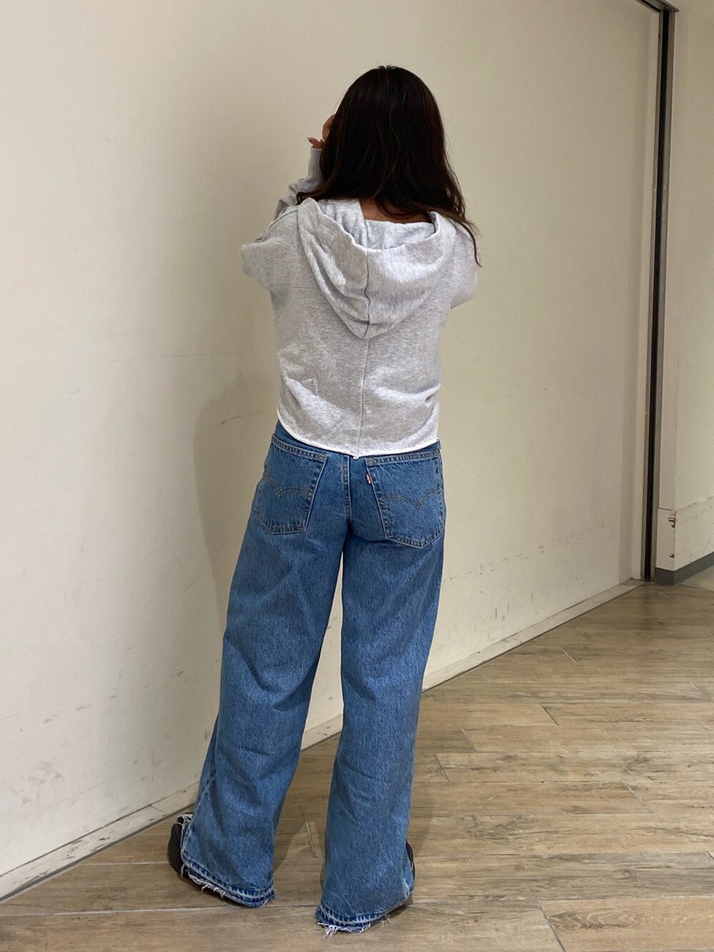 グレー系のパーカー、ブルー系のデニムパンツを着用したレディースの秋コーディネートの3枚目の写真