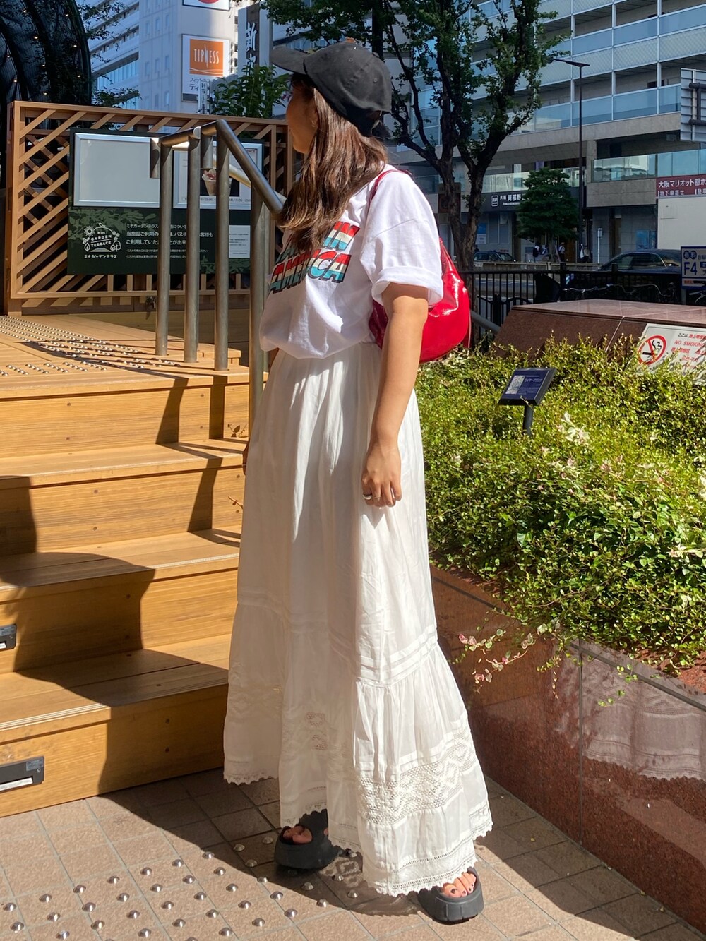 ホワイト系のTシャツ/カットソー、ホワイト系のスカート、ブラック系のキャップを着用したレディースの夏コーディネートの2枚目の写真